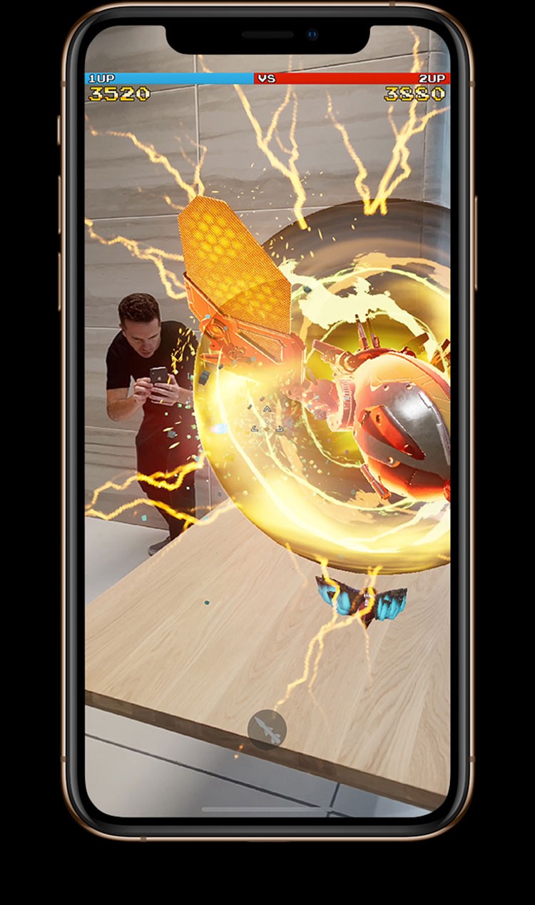iPhone XS・iPhone XS Maxの画面に男性が拡張現実（AR）の要素を取り入れたバトルゲームをしている画像