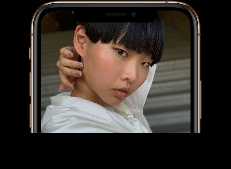 iPhone XS・iPhone XS MaxのTrueDepthカメラで、黒髪ベリーショート、前髪が眉毛の下でまっすぐ切り揃えられ、首の後ろに腕を回している女性を写している画像